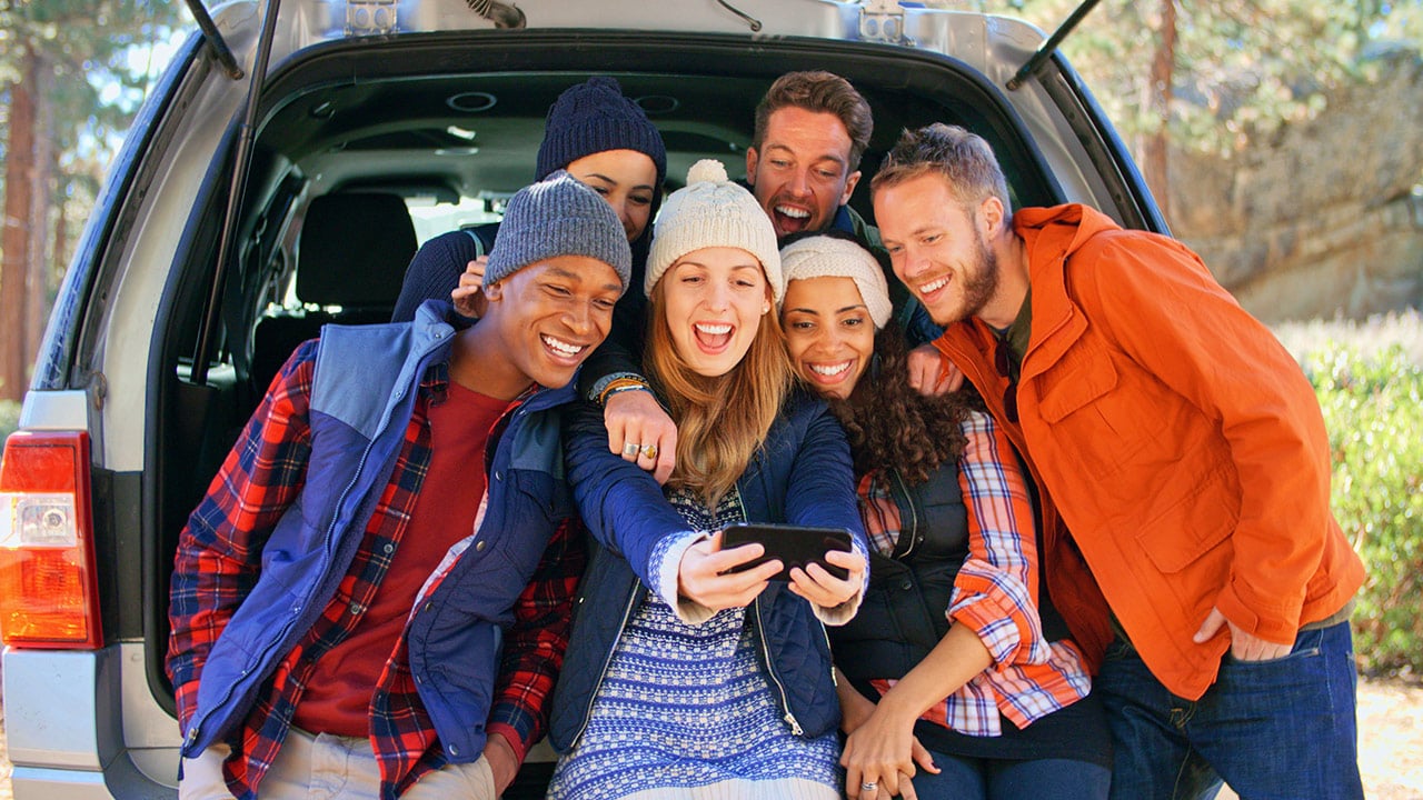 Friends taking a selfie in the back of a car. 