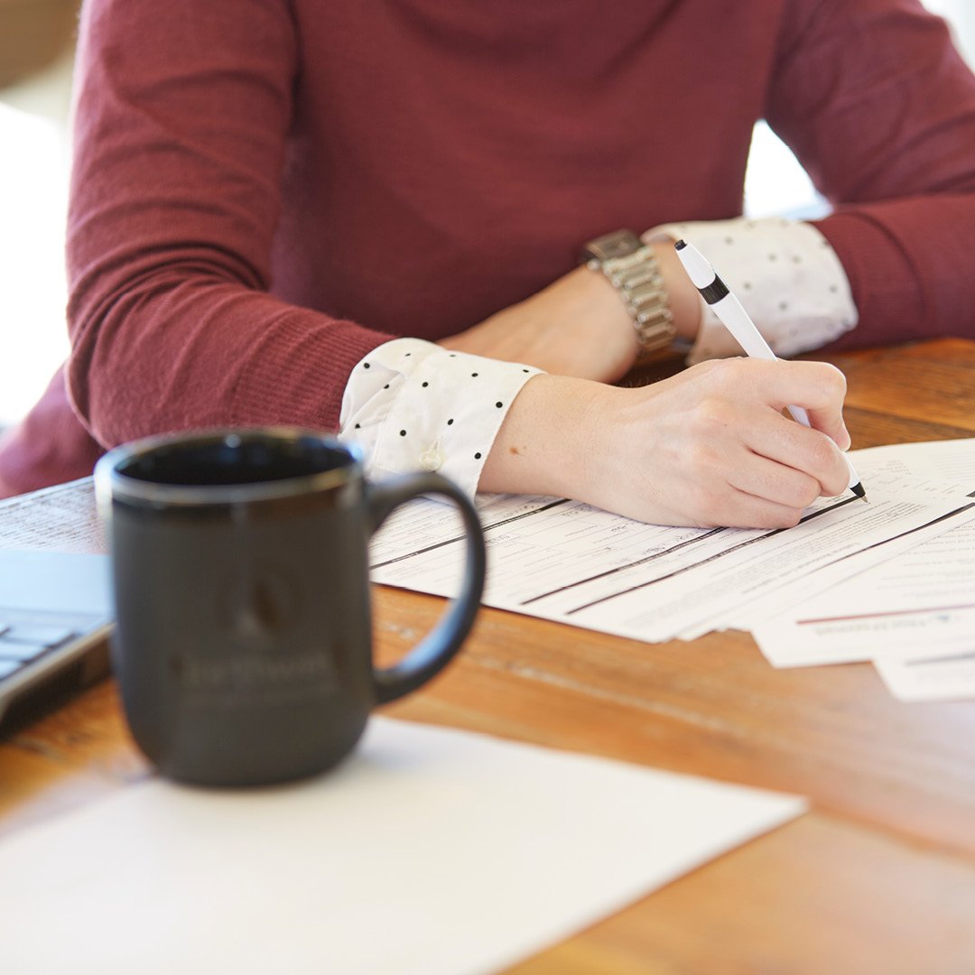 A peak employee writing on a paper form