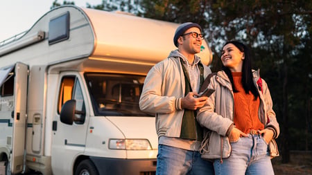 A couple posing in front of a camper. 