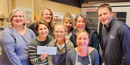 A group of school employees and foundation representatives posing with a check to pay off lunch debts
