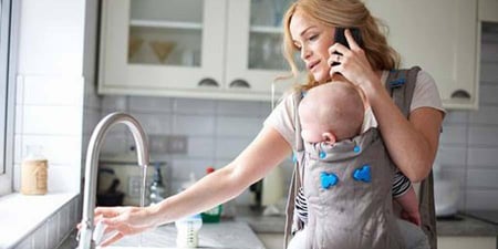 Woman with a baby an a call while in her kitchen