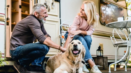 A women and man petting a dog in front of a RV