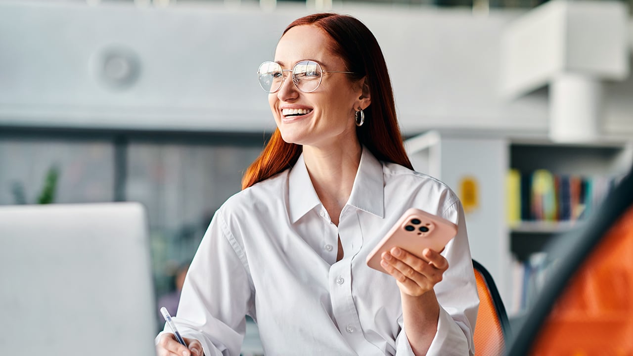A smiling women holding her phone. 