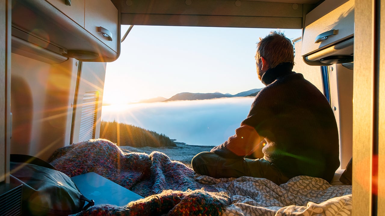 A man looking out at a lake from the back of his RV