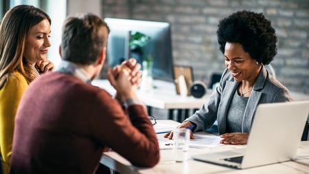 A smiling banker assisting a couple with forms