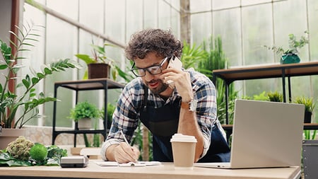 a person on the phone while writing something down on a paper. 