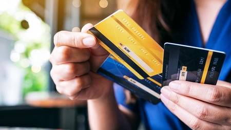 A close-up image of hands holding multiple credit cards