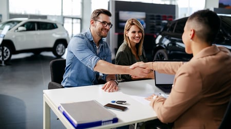 A couple meeting with an auto dealer to buy a car