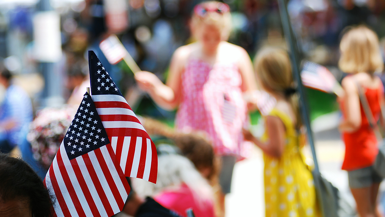 Hand holding two small American Flags.