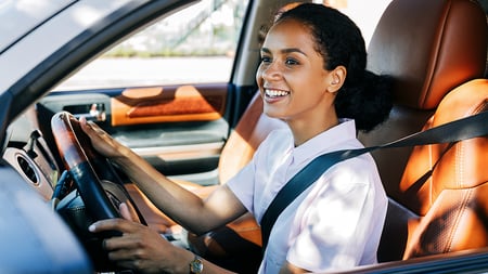 A smiling women driving a car